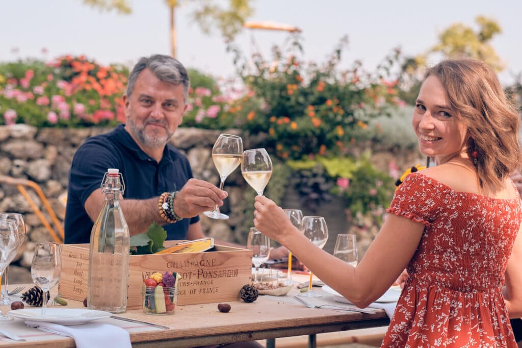 couple qui trinque avec deux coupes de champagne dans un jardin